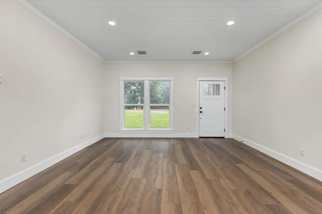 an empty room with wooden floor and windows
