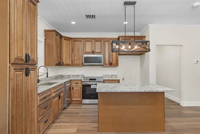 a kitchen with stainless steel appliances granite countertop a sink a stove and a wooden floors