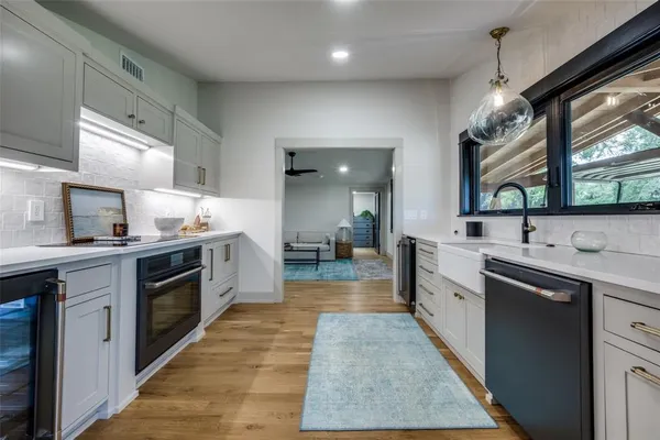 a large white kitchen with stainless steel appliances granite countertop a sink and dishwasher a stove with wooden floor