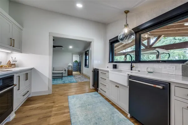 a kitchen with stainless steel appliances granite countertop sink stove and white cabinets with wooden floor