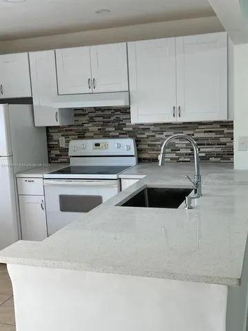 a kitchen with white cabinets and white appliances