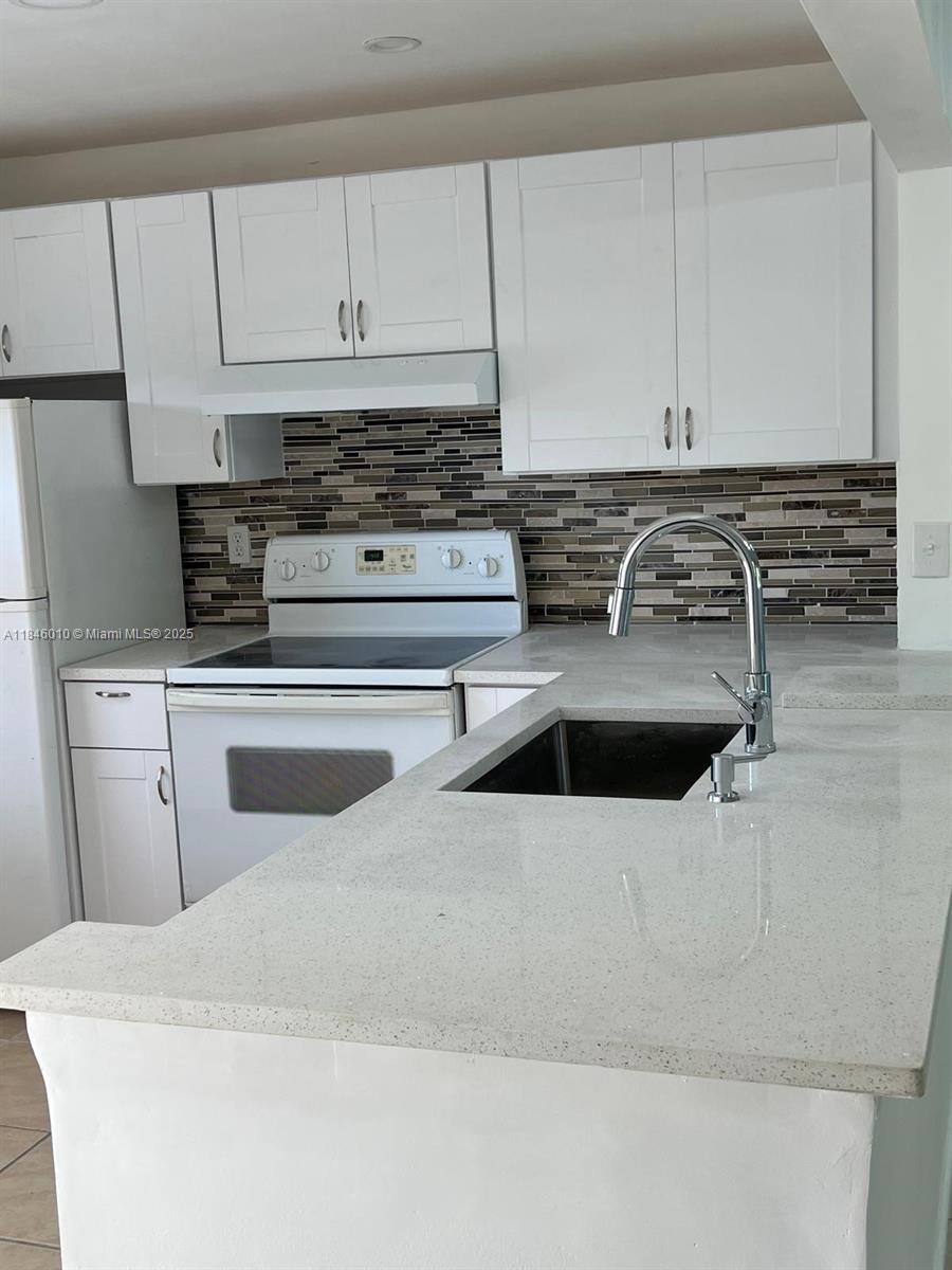 1015 Country Club Drive, Unit 302 Margate, FL 33063 - Photo 2 of 9 a kitchen with white cabinets and white appliances