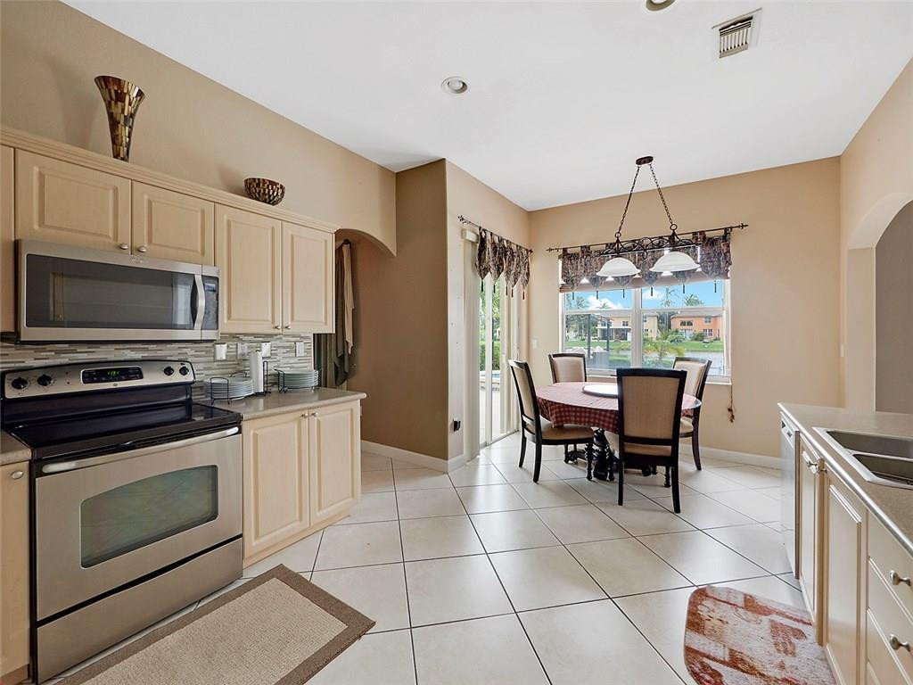 12980 Southwest 52nd Street Miramar, FL 33027 - Photo 7 of 17 a kitchen with kitchen island granite countertop a sink cabinets and stainless steel appliances