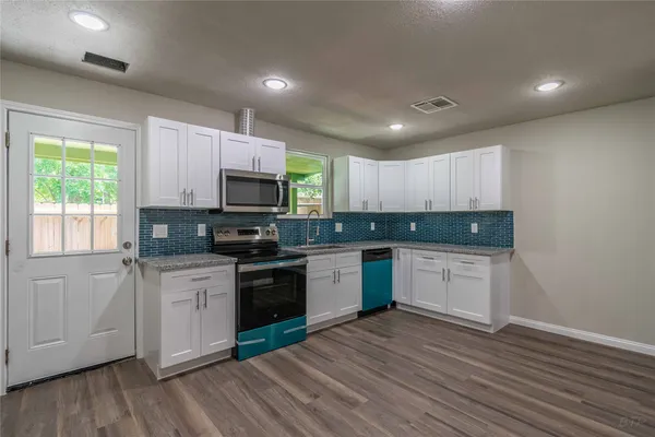 a kitchen with granite countertop a stove top oven sink and cabinets