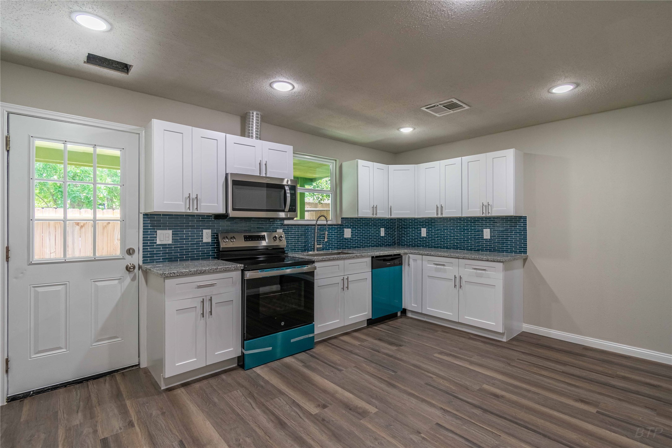 a kitchen with granite countertop a stove top oven sink and cabinets