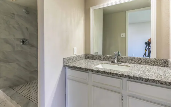 a bathroom with a granite countertop sink and a mirror