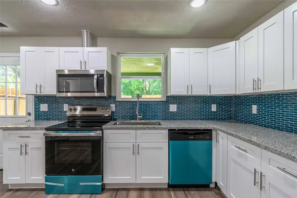 a kitchen with granite countertop a sink cabinets and stainless steel appliances