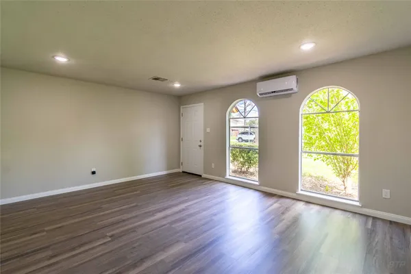 an empty room with wooden floor and windows