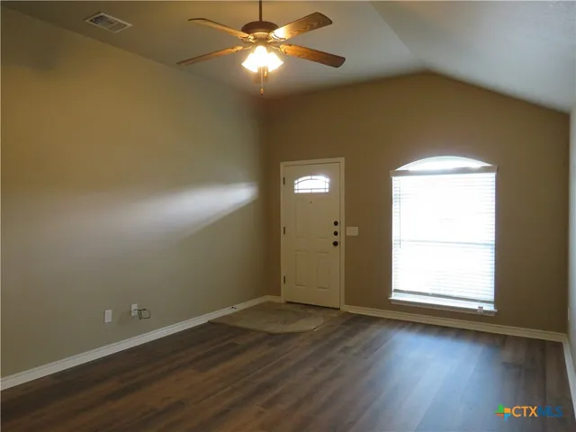 an empty room with wooden floor and windows