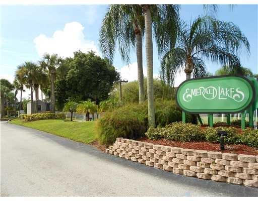 5768 Southeast Windsong Lane Stuart, FL 34997 - Photo 2 of 15 a sign board with a small yard and palm trees