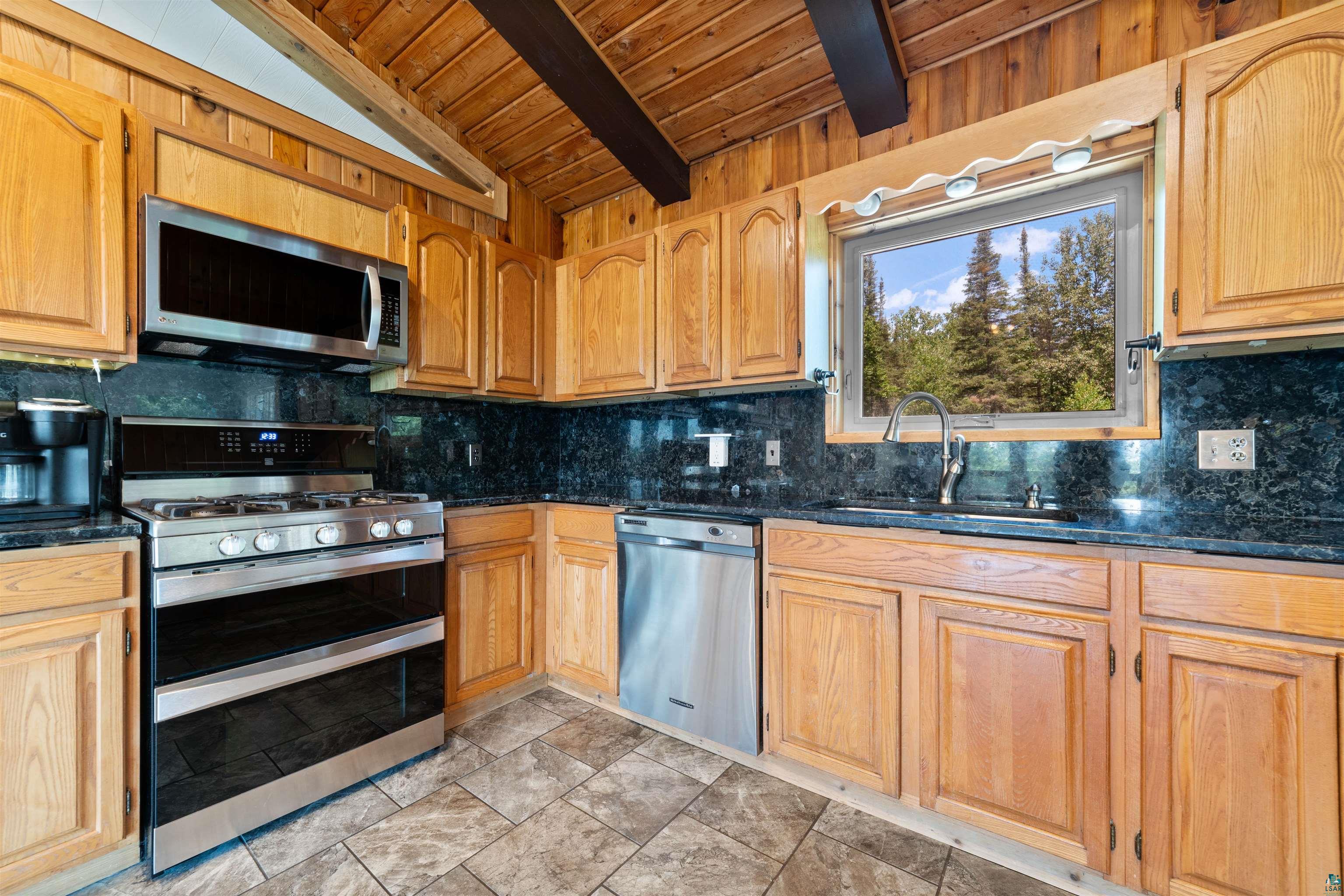 5235 Lakewood Road Duluth, MN 55804 - Photo 6 of 37 Kitchen with decorative backsplash, stainless steel appliances, light tile patterned flooring, and wood ceiling