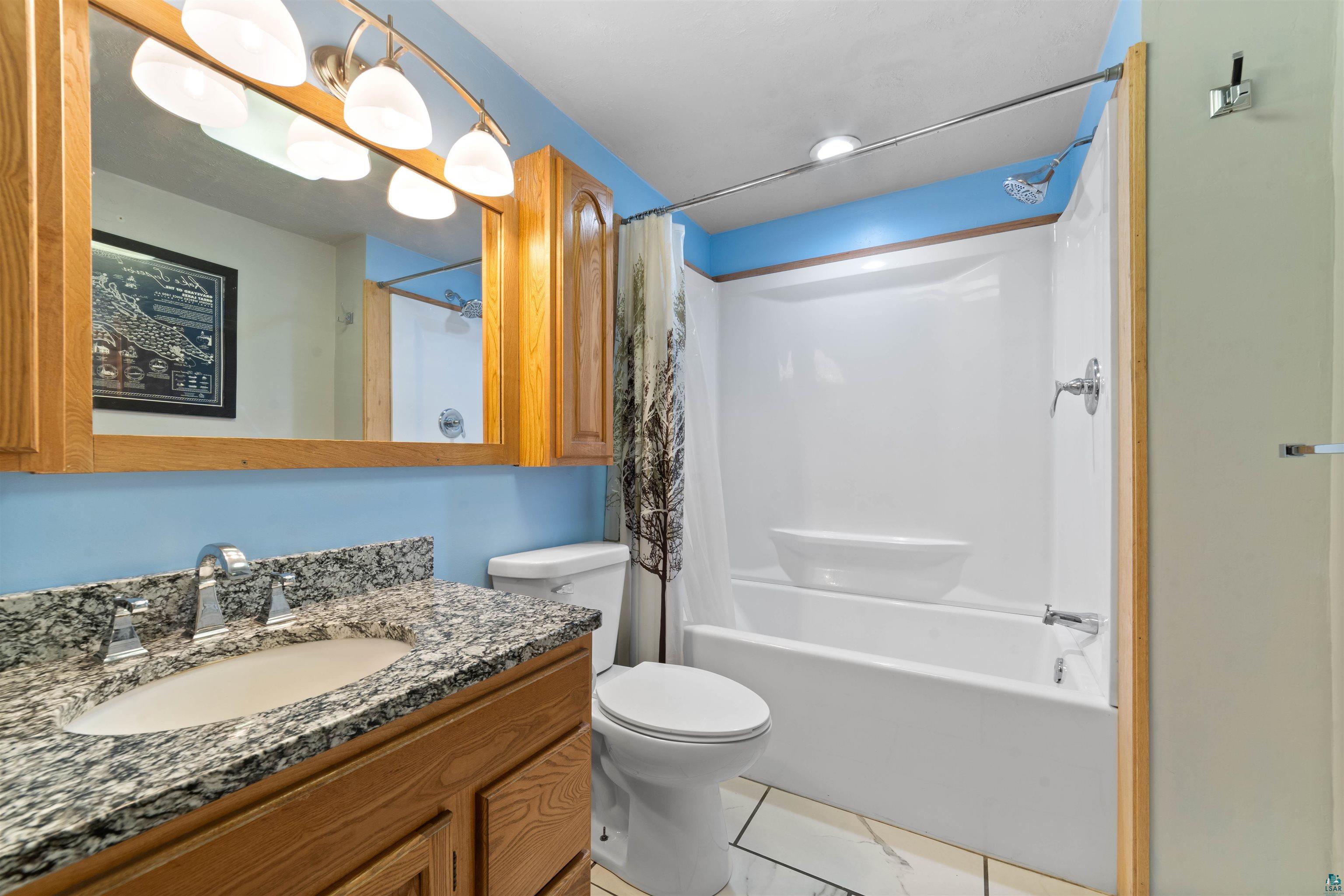 5235 Lakewood Road Duluth, MN 55804 - Photo 10 of 37 Full bathroom featuring vanity, tile patterned flooring, toilet, and shower / bath combo