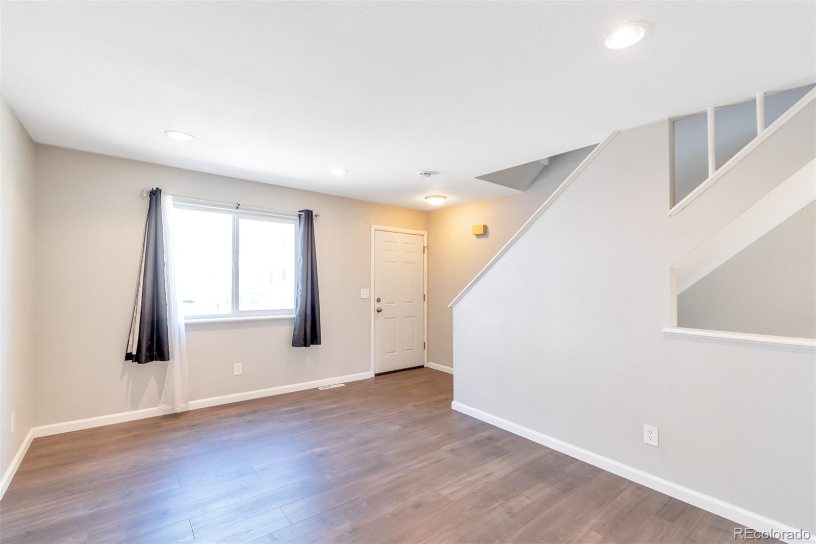 13488 East 13th Place Aurora, CO 80011 - Photo 3 of 15 an empty room with wooden floor and windows