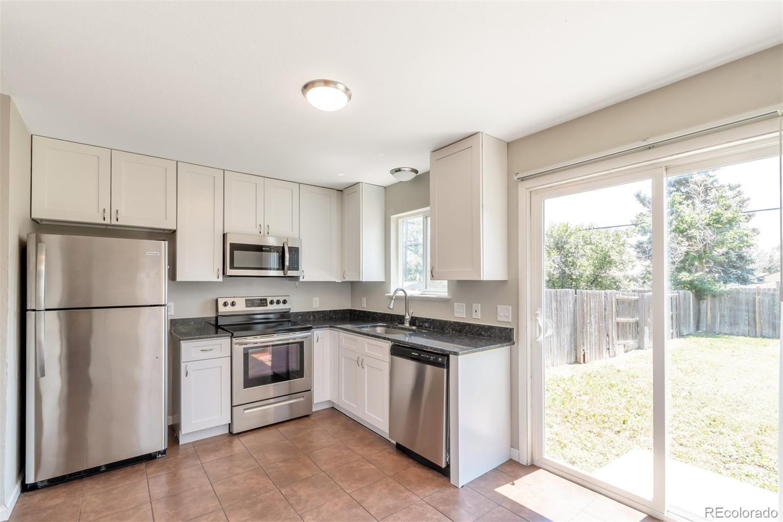 13488 East 13th Place Aurora, CO 80011 - Photo 5 of 15 a kitchen with white cabinets and white appliances