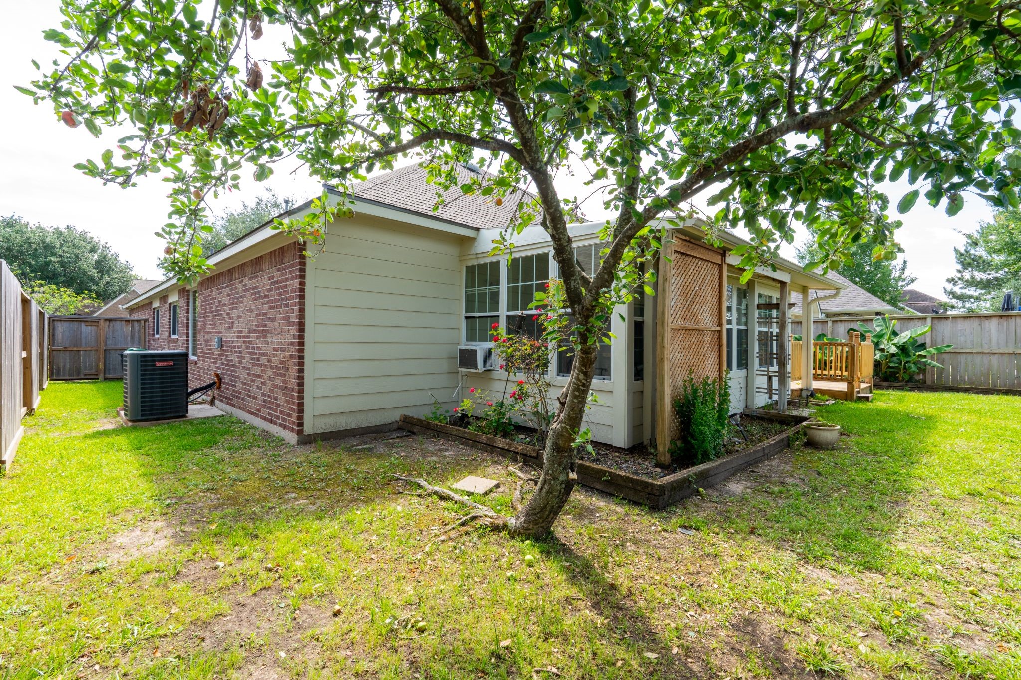 10619 Crownsedge Drive Spring, TX 77379 - Photo 33 of 38 Charming backyard with a well-maintained lawn, mature tree, and a brick and siding exterior. Features a small deck, garden beds, and privacy fencing, ideal for outdoor enjoyment.