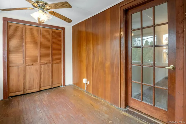a view of empty room with wooden floor and fan
