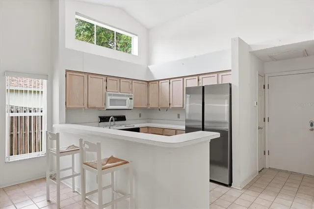 a kitchen with stainless steel appliances granite countertop a sink a stove a refrigerator a washer and dryer next to a window