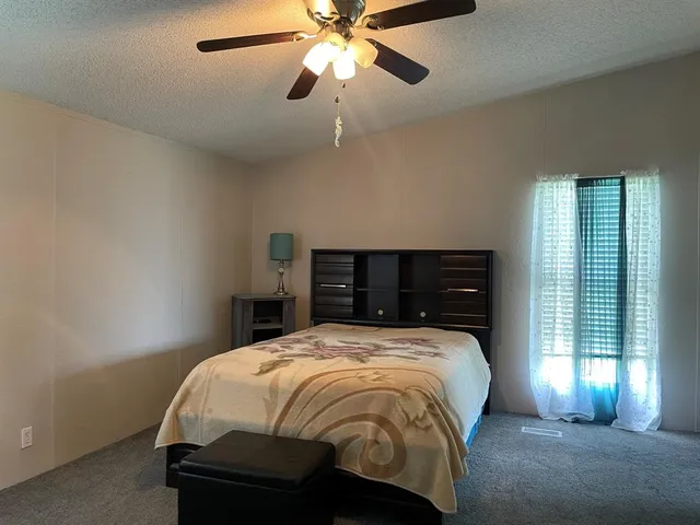 a bed sitting in a bedroom next to a window and a chandelier