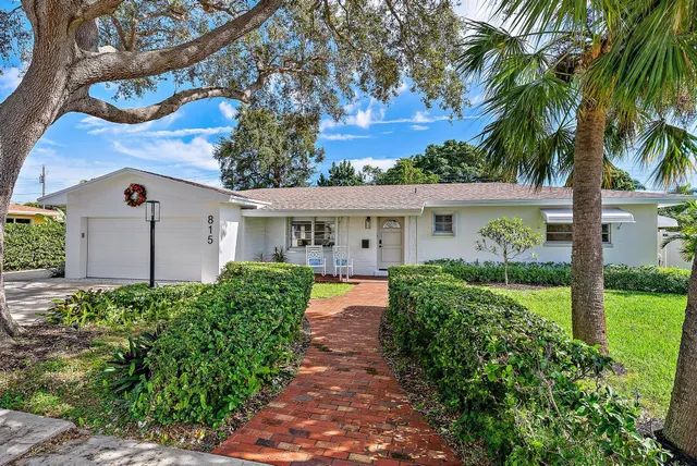 a front view of a house with garden and plants