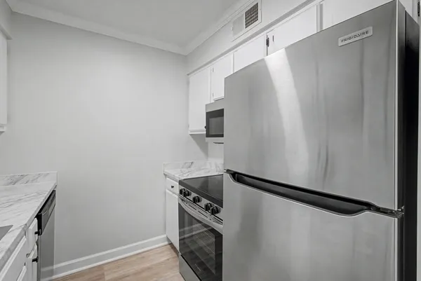 a kitchen with a refrigerator and white cabinets
