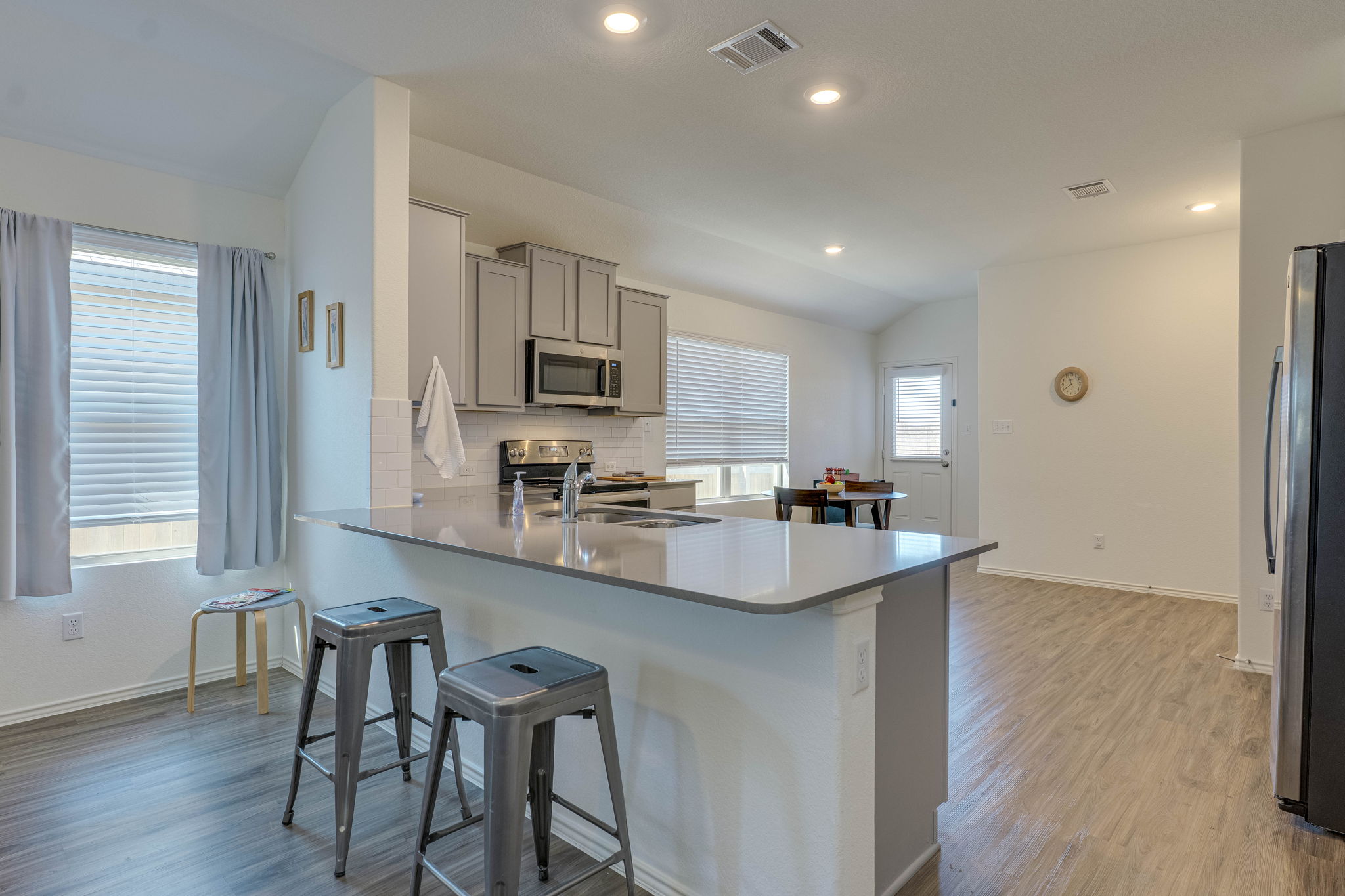 557 Greatest Gift Way Jarrell, TX 76537 - Photo 11 of 39 Kitchen with vaulted ceiling, light wood-style floors, stainless steel appliances, gray cabinets, and a peninsula