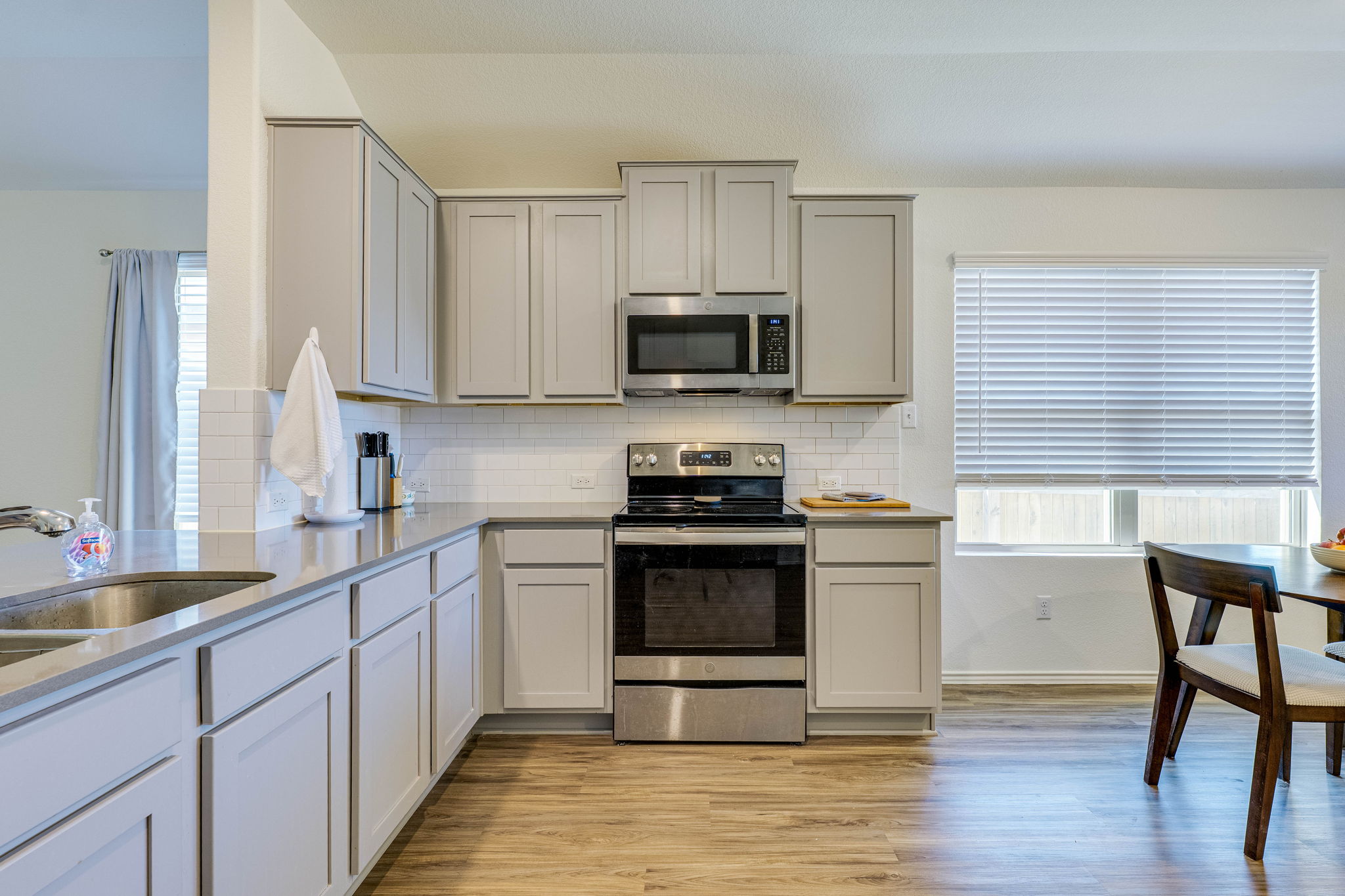 557 Greatest Gift Way Jarrell, TX 76537 - Photo 12 of 39 Kitchen with stainless steel appliances, light stone countertops, light wood finished floors, and gray cabinets