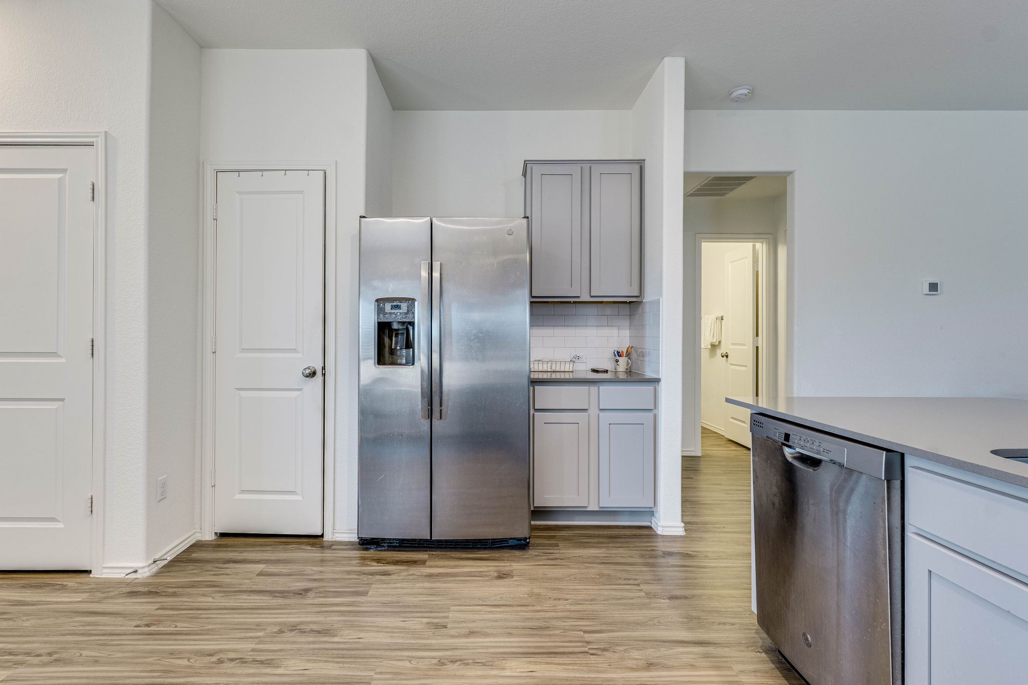 557 Greatest Gift Way Jarrell, TX 76537 - Photo 14 of 39 Kitchen with stainless steel appliances, gray cabinetry, light wood finished floors, decorative backsplash, and dark stone countertops