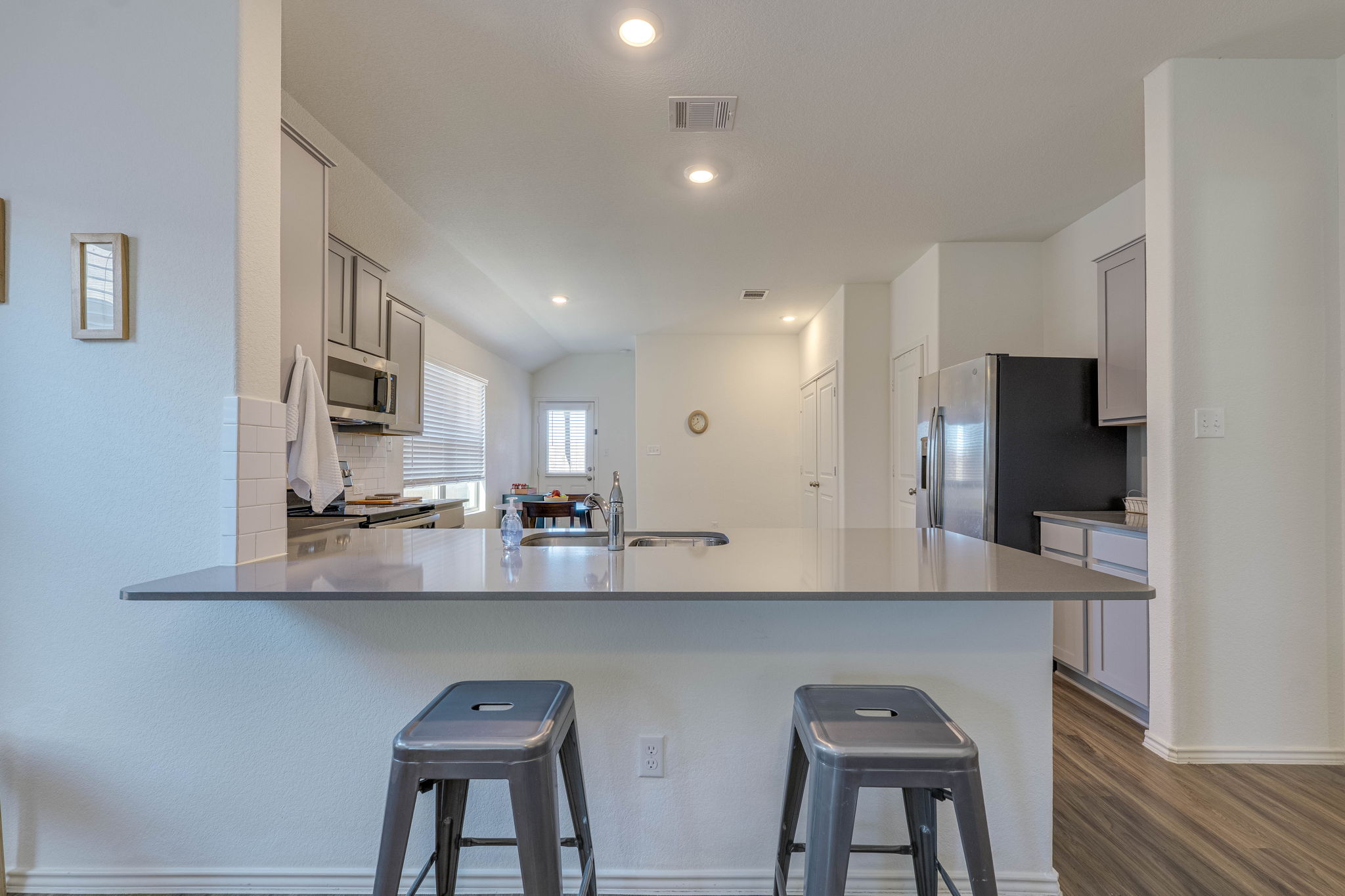 557 Greatest Gift Way Jarrell, TX 76537 - Photo 9 of 39 Kitchen with a peninsula, stainless steel appliances, dark wood finished floors, recessed lighting, and light stone counters