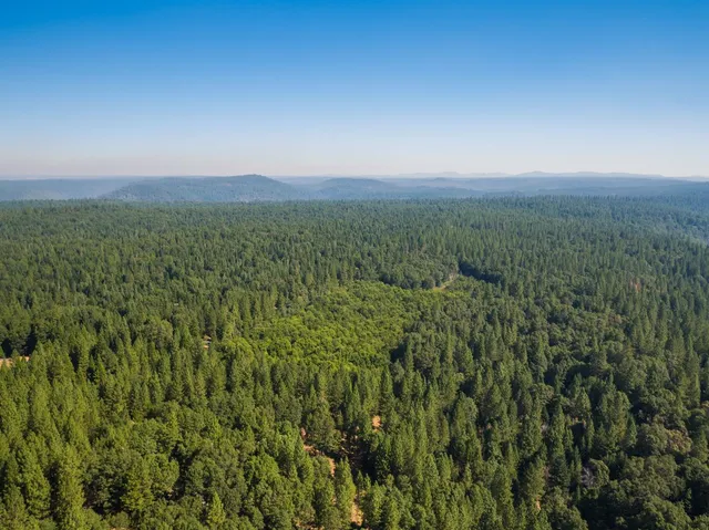an aerial view of house with yard and mountain view in back