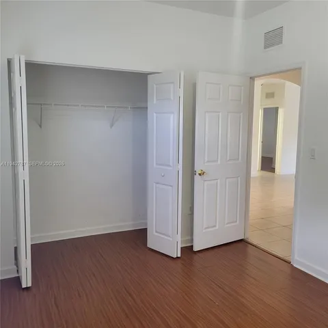 an empty room with wooden floor & closet area