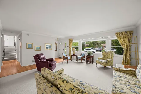a living room with furniture large window and wooden floor