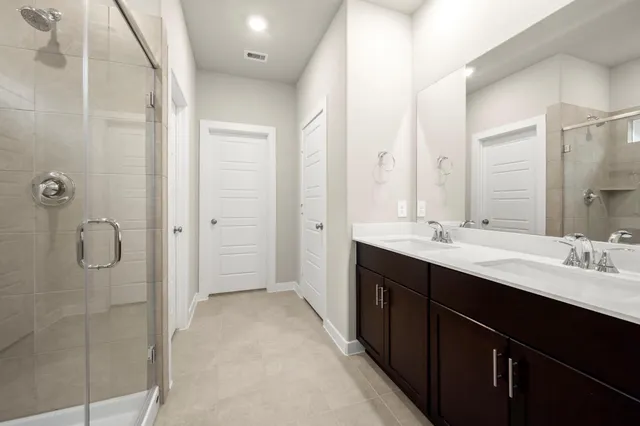 a bathroom with a double vanity sink mirror and shower