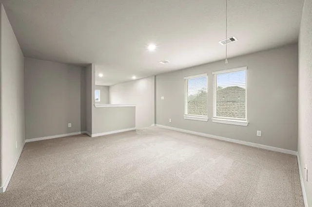 a view of an empty room with a window and a kitchen