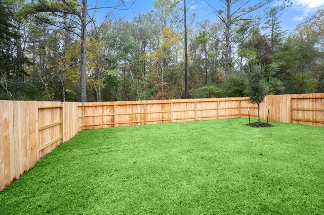 a view of a backyard with grass and wooden fence