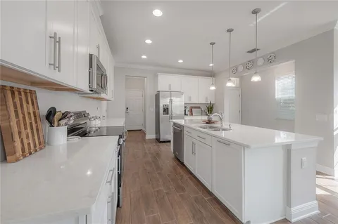 a large kitchen with kitchen island a sink a center island stainless steel appliances and a counter top space