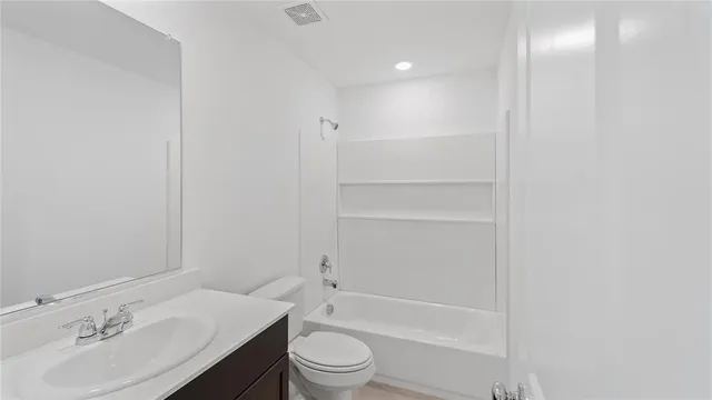 a bathroom with a bathtub shower sink vanity mirror and toilet