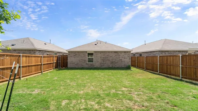a view of a backyard with brick wall and a large tree