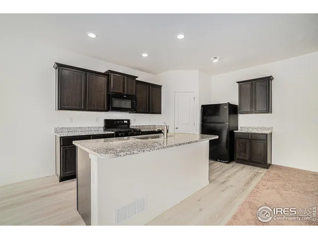 a kitchen with stainless steel appliances granite countertop a stove a sink and a refrigerator with wooden floor