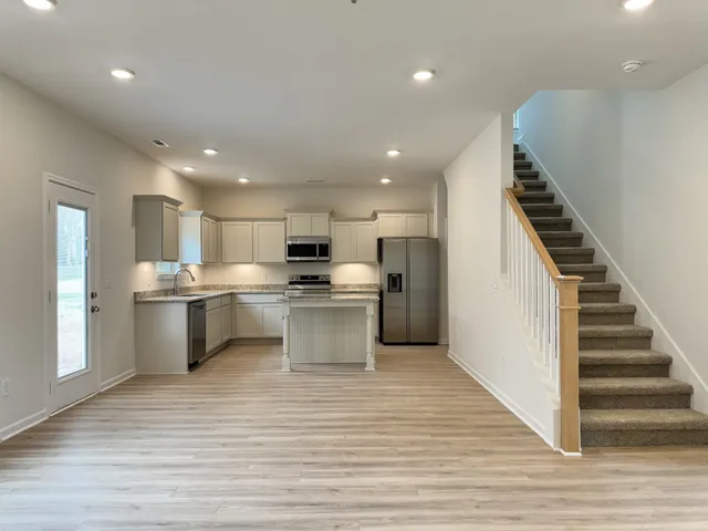 a large white kitchen with kitchen island a sink stainless steel appliances and cabinets