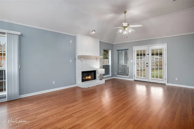 a view of an empty room with wooden floor fireplace and a window