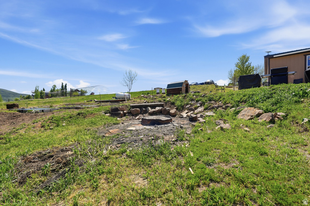 8066 North Valley View Heights Preston, ID 83263 - Photo 27 of 34 Expansive outdoor area featuring a built-in stone fire pit, rock landscaping, and a sloped grassy terrain