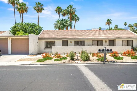 a front view of a house with a yard and potted plants