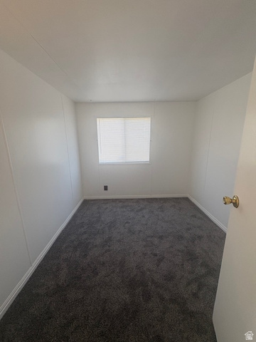 1111 North 2000 West, Unit 293 Farr West, UT 84404 - Photo 9 of 13 Neutral-toned room featuring a single window with blinds, dark gray carpet, white walls, and white baseboards