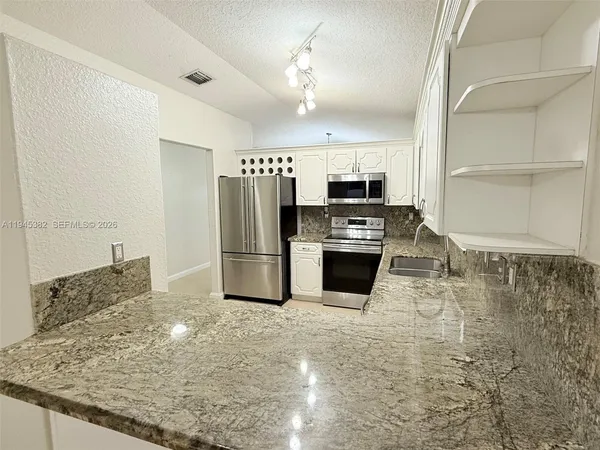 a kitchen with stainless steel appliances granite countertop a stove a sink and a refrigerator