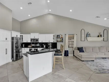 a kitchen with stainless steel appliances kitchen island granite countertop a refrigerator and cabinets
