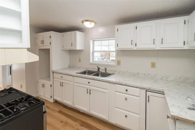 a kitchen with granite countertop white cabinets and stainless steel appliances
