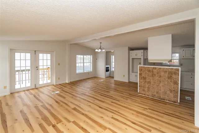 a view of an empty room with window and wooden floor