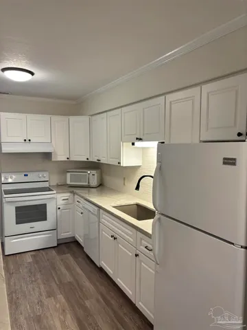 a kitchen with granite countertop a sink dishwasher a stove and cabinets