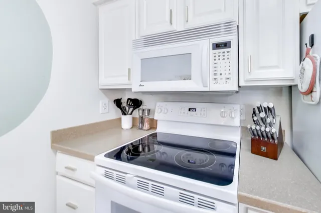 a kitchen with white cabinets and appliances