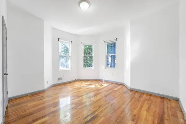 a view of empty room with window and wooden floor